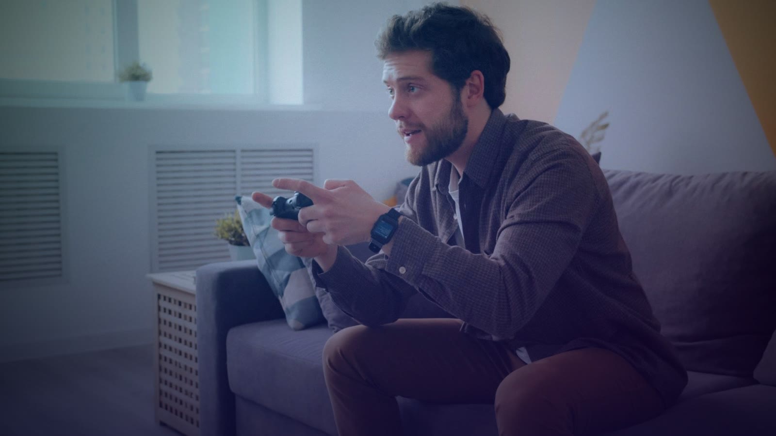 A man focused on playing video games on a console in a modern living room setting.