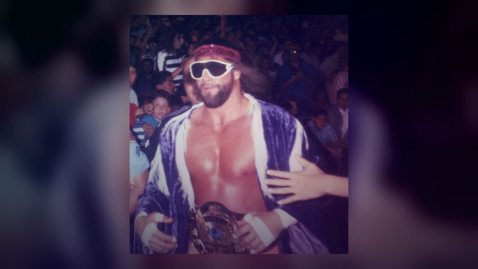 Professional wrestler Randy 'Macho Man' Savage wearing the WWF Championship belt, running to the ring in his characteristic wrestling attire during a 1989 WWF event