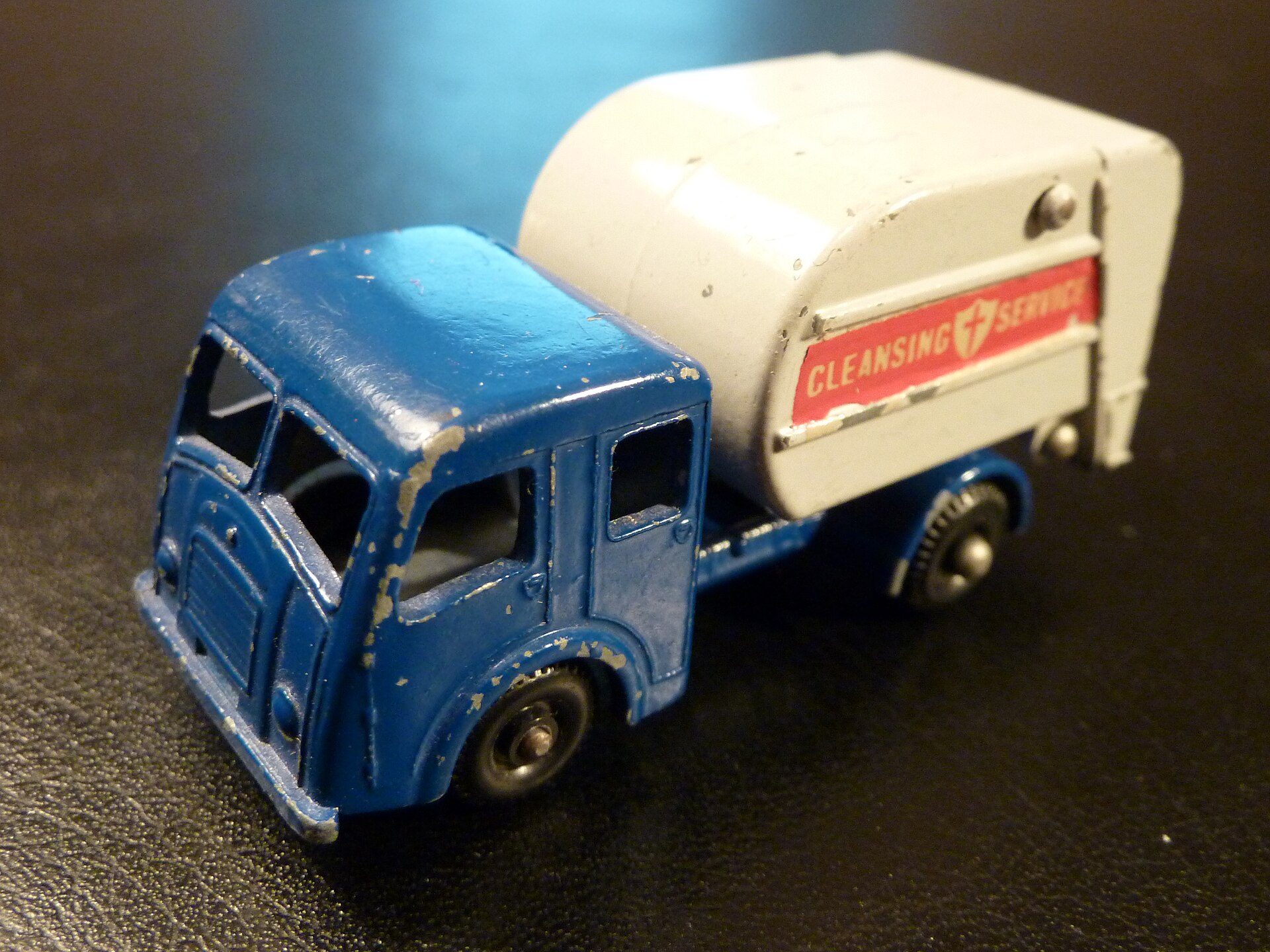 A Matchbox toy car from 1963 - a Tippax refuse collector model number 15 with regular wheels, photographed against a black mat with professional lighting