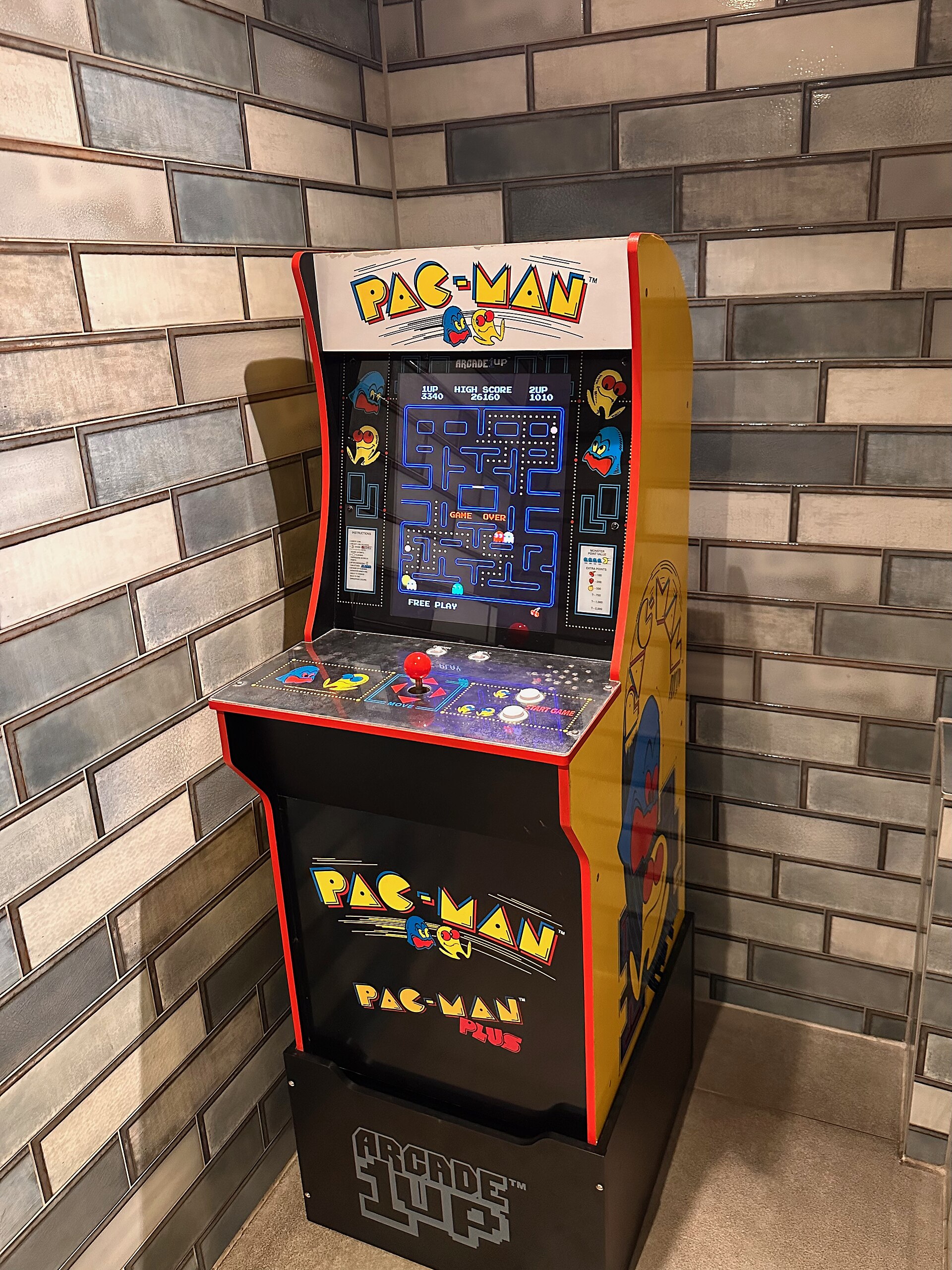 A modern Arcade1Up Pac-Man arcade cabinet in a restaurant setting, showing a contemporary arcade machine suitable for game rooms and man caves