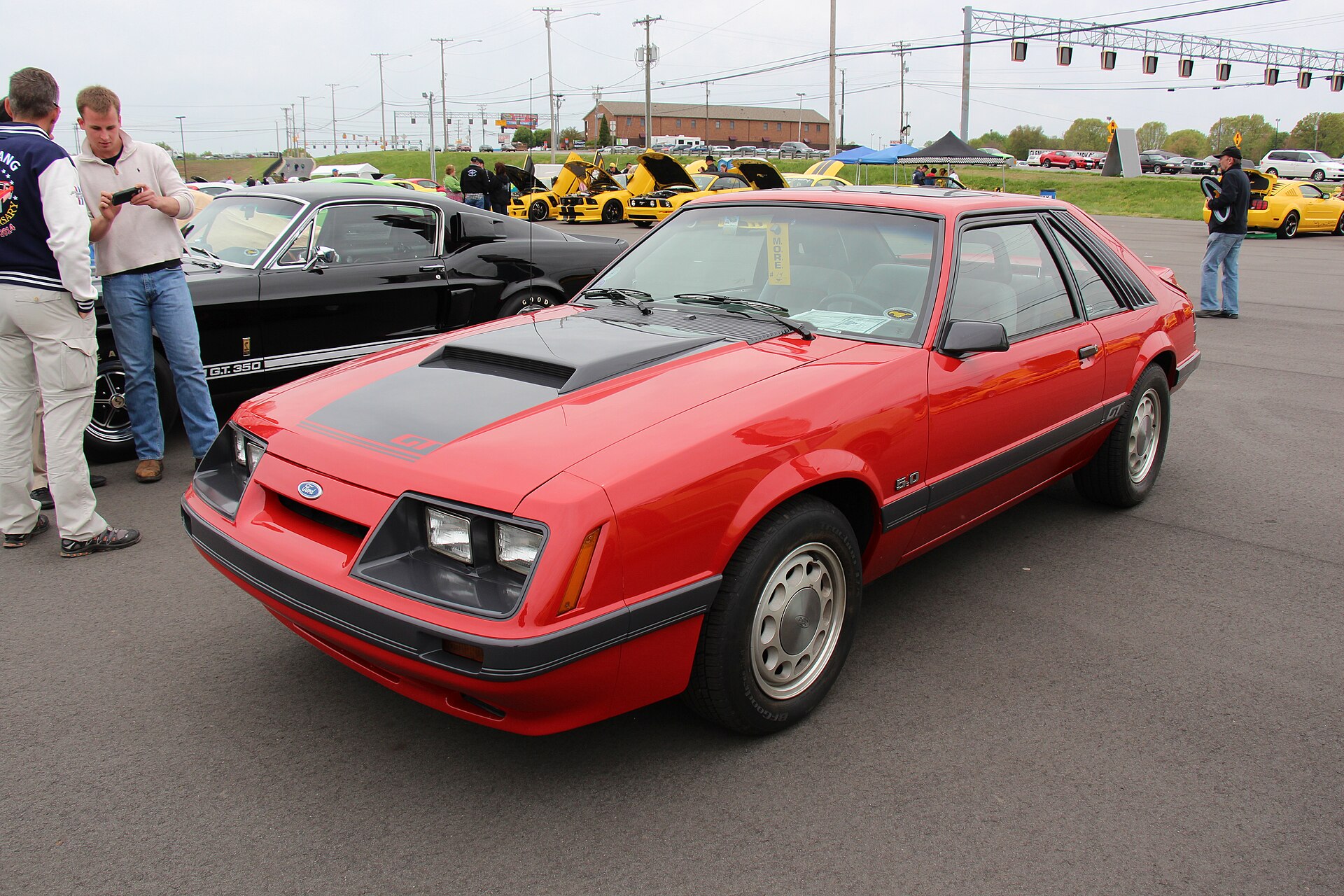 A bright red 1986 Ford Mustang GT hatchback, a classic Fox body Mustang from the mid-1980s era