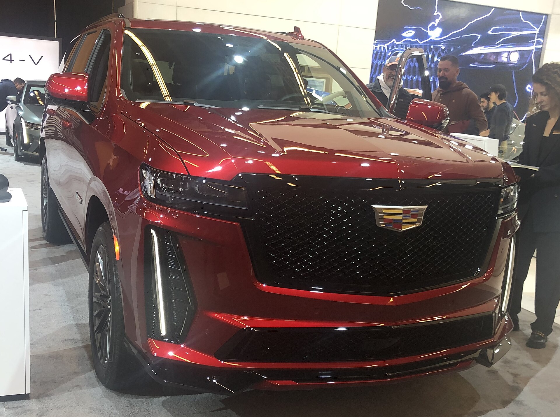 2023 Cadillac Escalade V photographed at an auto show, showing front and side profile of the SUV